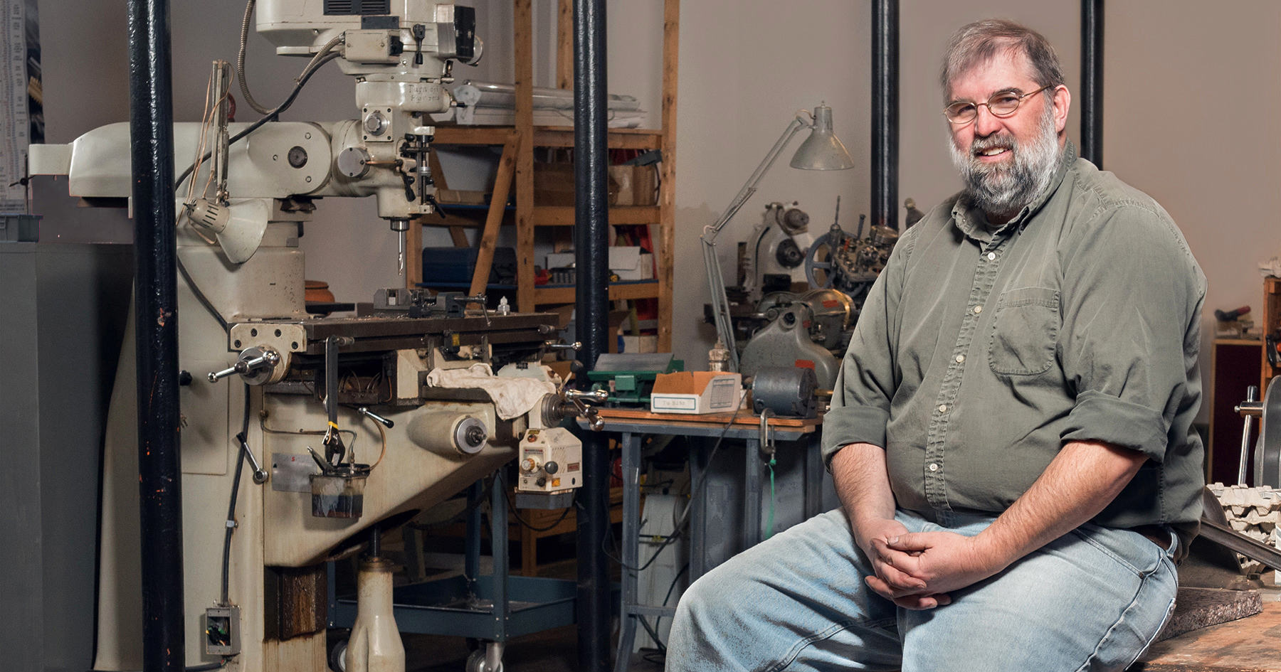 Jonathan Larrabee, the face of HMH Fly Tying Vises, sits with a newly finished vise in his shop at the Pepperell Mill Campus, photographed by Portland Headshot.