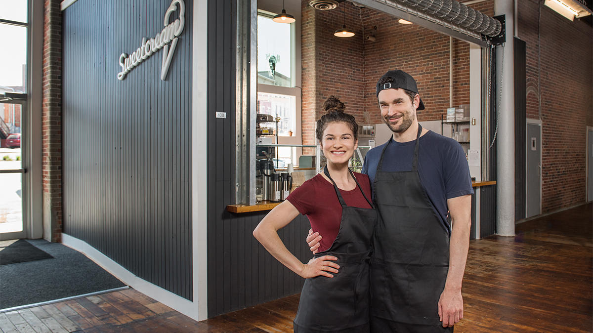 Jackie and Jon, just before their wedding, standing in front of their venture together, making homemade ice cream at Sweetcream Dairy in the Pepperell Mill Campus. Photograph by Portland Headshot